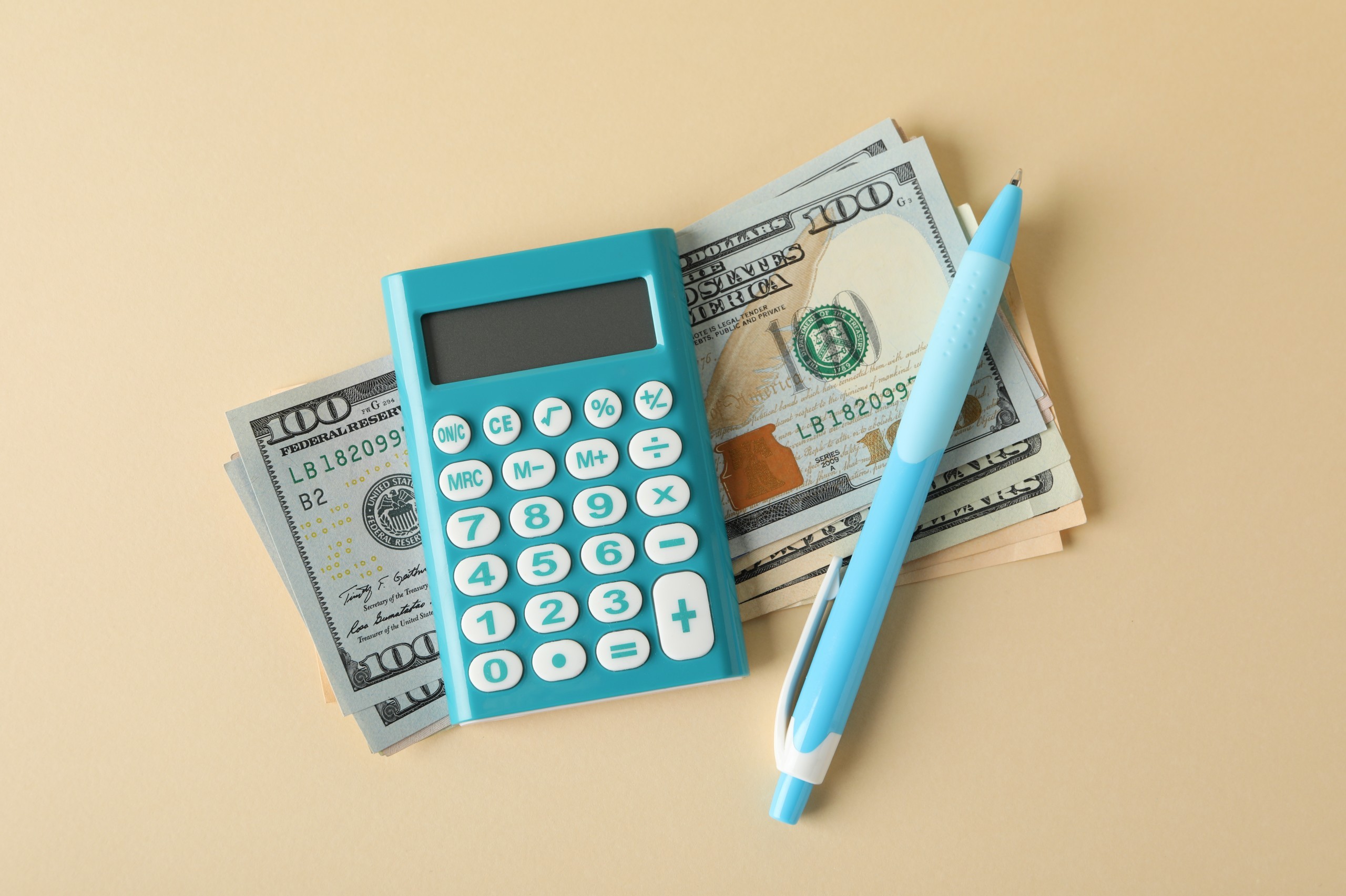 geld-taschenrechner-und-stift-auf-beige-draufsicht.jpg