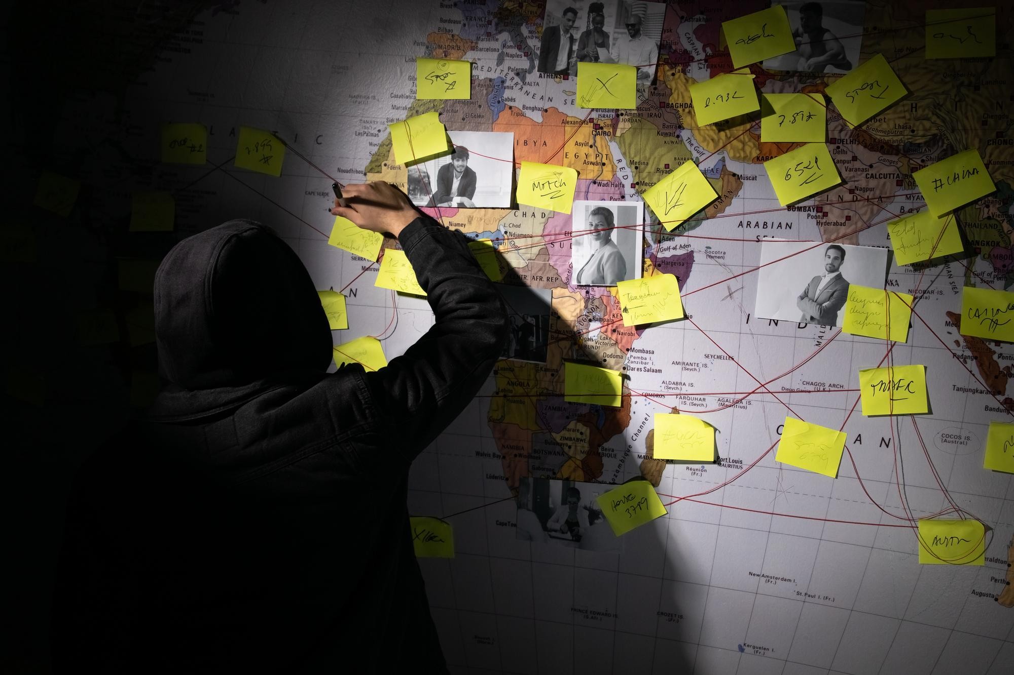 Illustration of a criminal mapping out routes on a world map