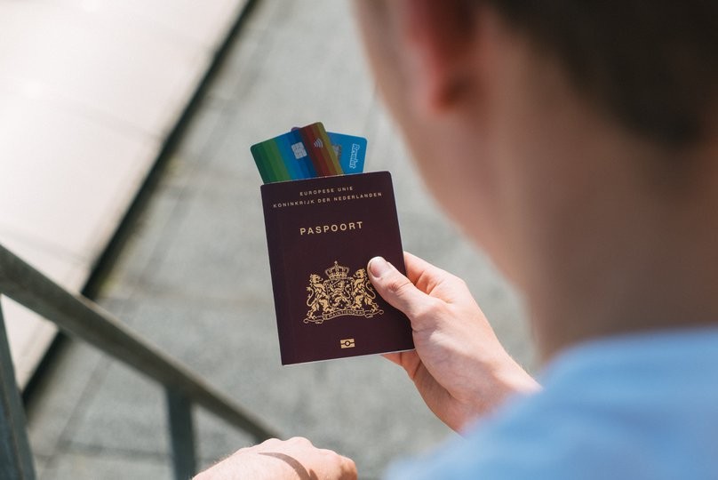 A person holding a passport and two microchip-cards